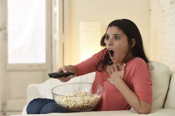 Łacińskiej kobieta siedzi w domu rozkładana kanapa w salonie, oglądając film straszny horror telewizyjny — Zdjęcie stockowe