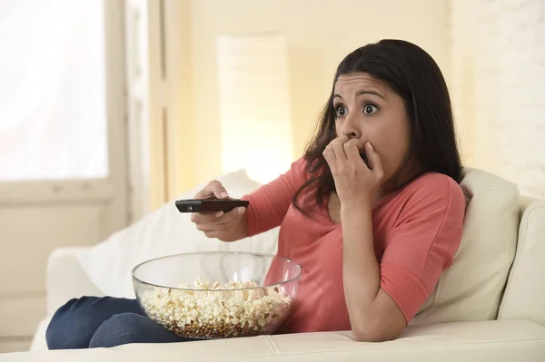 Λατινική γυναίκα κάθεται στο σπίτι και καναπέ-κρεβάτι στο σαλόνι βλέποντας τηλεόραση τρομακτικό φρίκη ταινία — Φωτογραφία Αρχείου