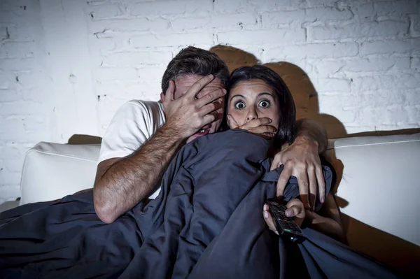 Atractiva pareja en casa disfrutando viendo televisión horror película cubierta con manta — Foto de Stock