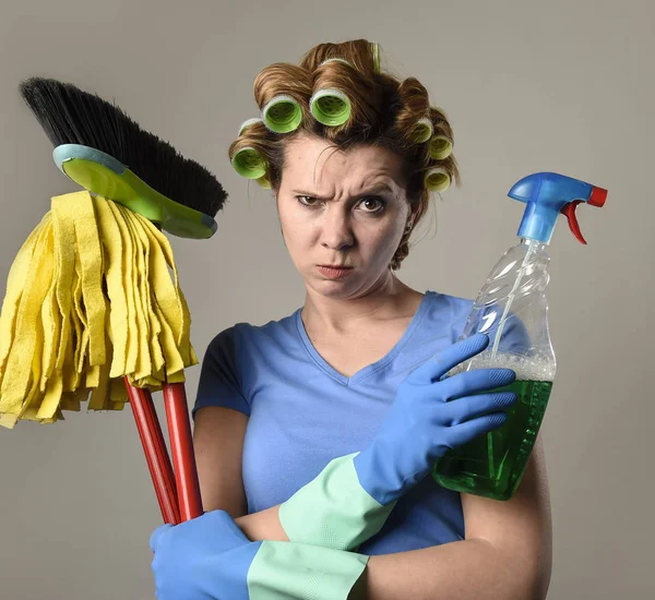 housewife in rubber gloves and hair rollers holding cleaning spr