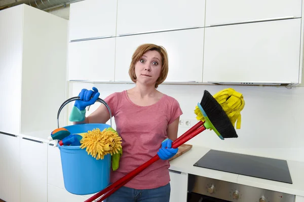 Femme au foyer à la maison cuisine dans des gants tenant balai de nettoyage et balai et seau — Photo