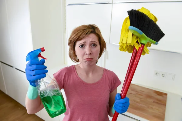 Housewife at home kitchen in gloves holding cleaning broom and mop and spray bottle — Stock Photo, Image