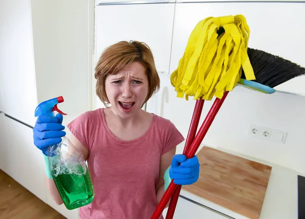 Femme au foyer à la maison cuisine dans des gants tenant balai de nettoyage et la serpillière et vaporisateur — Photo