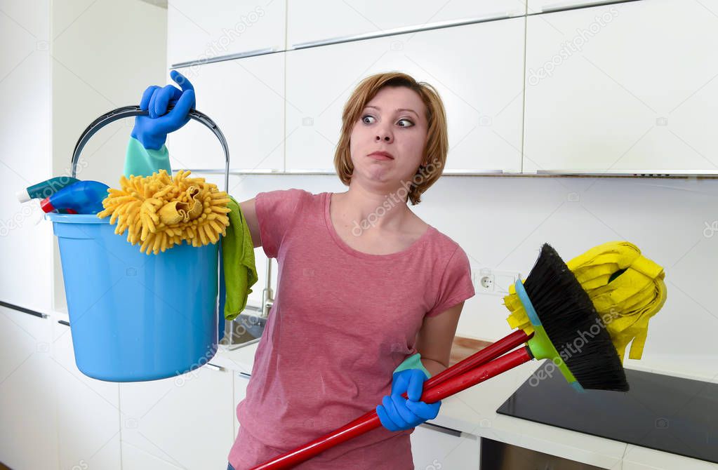 housewife at home kitchen in gloves holding cleaning broom and mop and bucket