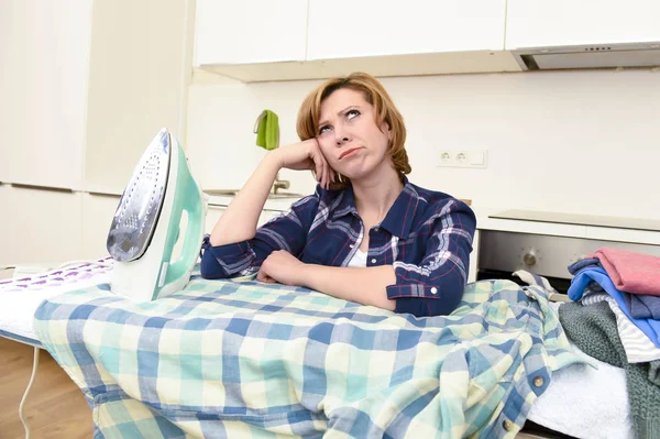 Traurige Frau oder geschäftige Hausfrau, die in der heimischen Küche faul Hemd bügelt — Stockfoto