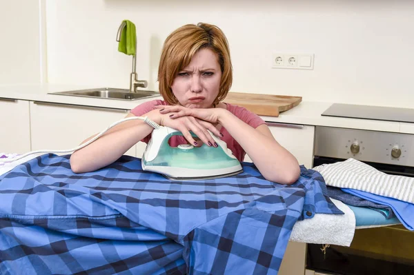 Treurige vrouw of drukke huisvrouw strijken shirt lui bij u thuis keuken — Stockfoto