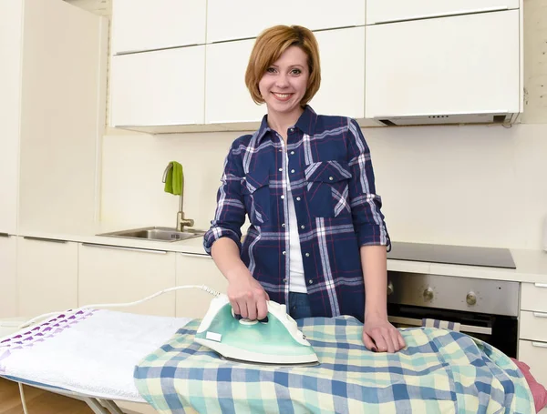 Lycklig kvinna eller hemmafru Strykningsservice skjorta på hem kök med iro — Stockfoto