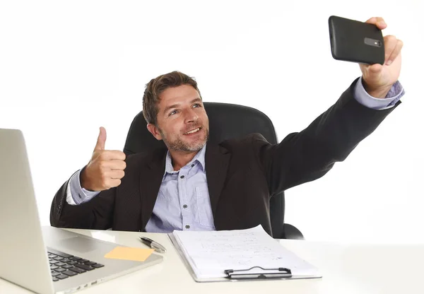 Affärsman i kostym som arbetar på kontor laptop dator skrivbord med hjälp av mobiltelefon för att ta selfie foto — Stockfoto