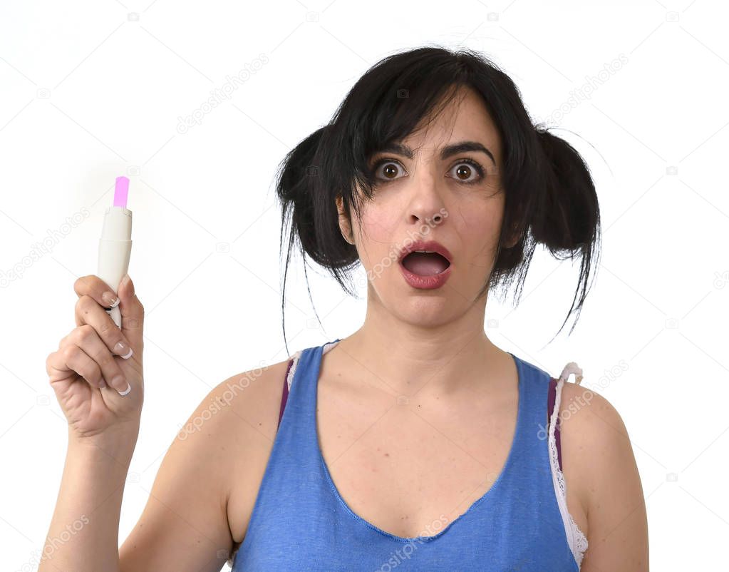 young pregnant woman scared in shock checking pink positive result on pregnancy test