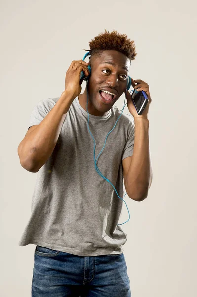 Black student man with headphones and mobile phone listening to music dancing and singing — Stock Photo, Image