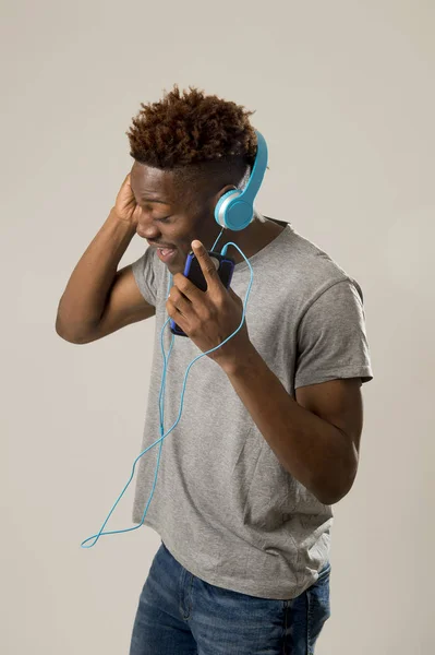 Black student man with headphones and mobile phone listening to music dancing and singing — Stock Photo, Image