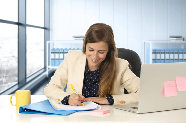 Mujer de 30 años en la oficina trabajando en el escritorio de la computadora portátil tomando notas — Foto de Stock