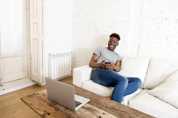 Zwarte man banklaag werken met de laptop en mobiele telefoon om thuis te zitten — Stockfoto