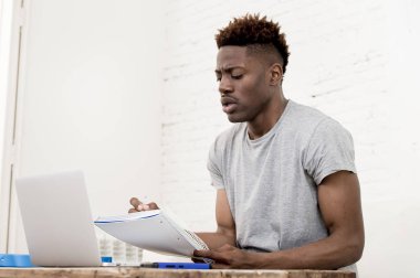 Afrika kökenli Amerikalı adam evde oturan salon dizüstü bilgisayar ve evrak ile çalışma