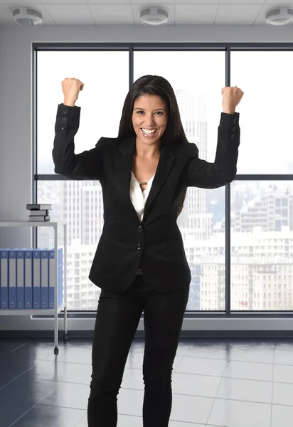 Женщина в формальном костюме улыбается счастливой и уверенной в себе в современном офисе — стоковое фото