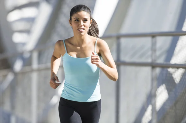 Junge schöne athletische Sportlerin läuft und joggt über moderne metallene Stadtbrücke — Stockfoto