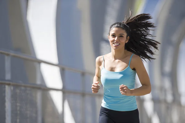 Junge schöne athletische Sportlerin läuft und joggt über moderne metallene Stadtbrücke — Stockfoto