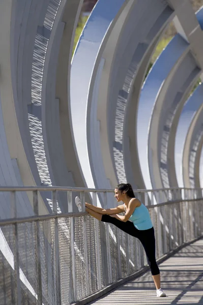 Νέοι όμορφη αθλητική sport γυναίκα διατάσεις μετά την εκτέλεση διέλευση σύγχρονη πόλη μεταλλική γέφυρα — Φωτογραφία Αρχείου