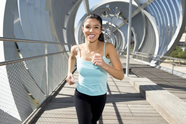 Junge schöne athletische Sportlerin läuft und joggt über moderne metallene Stadtbrücke — Stockfoto