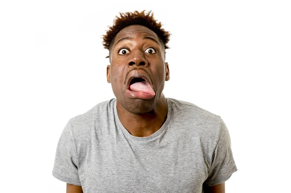 Афро-американец выглядит счастливым и игривым жестом, показывающим шокированное или глупое выражение лица — стоковое фото