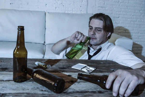 Homme alcoolique et toxicomane gaspillé avec cravate lâche sniffant de la cocaïne et buvant des bouteilles de bière à la maison — Photo