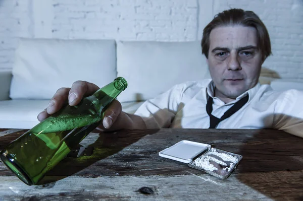 Hombre alcohólico y drogadicto desperdiciado con corbata suelta inhalando cocaína y bebiendo botellas de cerveza en casa —  Fotos de Stock