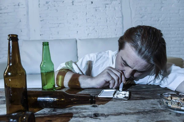 Nevyužité alkoholu a drog narkoman muž s volnou kravatu šňupání kokainu a pivní láhve pití doma — Stock fotografie