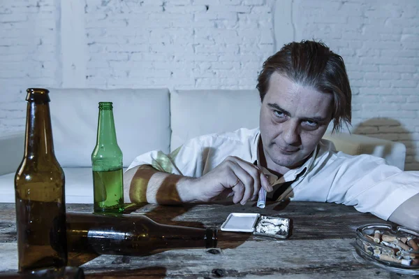 Nevyužité alkoholu a drog narkoman muž s volnou kravatu šňupání kokainu a pivní láhve pití doma — Stock fotografie
