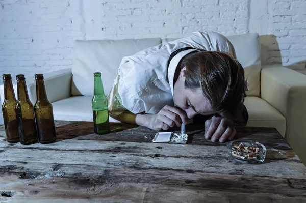 Adam kokain burundan enfiye şeklinde çekmek ve bira şişeleri evde içme gevşek kravatla boşa alkolik ve uyuşturucu bağımlısı — Stok fotoğraf