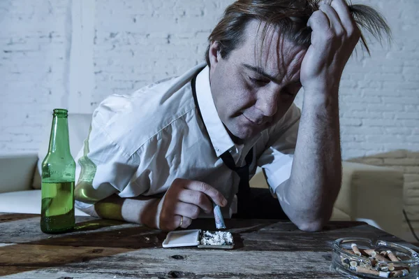 Homme alcoolique et toxicomane gaspillé avec cravate lâche sniffant de la cocaïne et buvant des bouteilles de bière à la maison — Photo