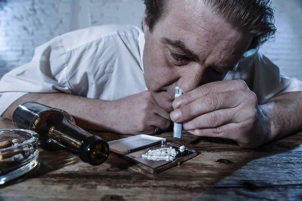 Zmarnowane alkoholu i narkotyków nałogowiec człowiek luźne krawat parskanie kokainy i picia butelki piwa w domu — Zdjęcie stockowe