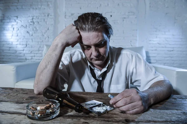 Hombre alcohólico y drogadicto desperdiciado con corbata suelta inhalando cocaína y bebiendo botellas de cerveza en casa — Foto de Stock