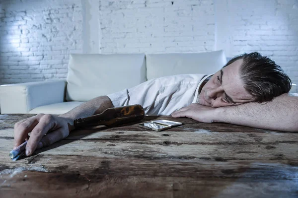 Homem alcoólatra e drogado desperdiçado com gravata solta roncando cocaína e bebendo garrafas de cerveja em casa — Fotografia de Stock