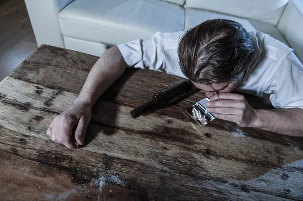 Homem alcoólatra e drogado desperdiçado com gravata solta roncando cocaína e bebendo garrafas de cerveja em casa — Fotografia de Stock