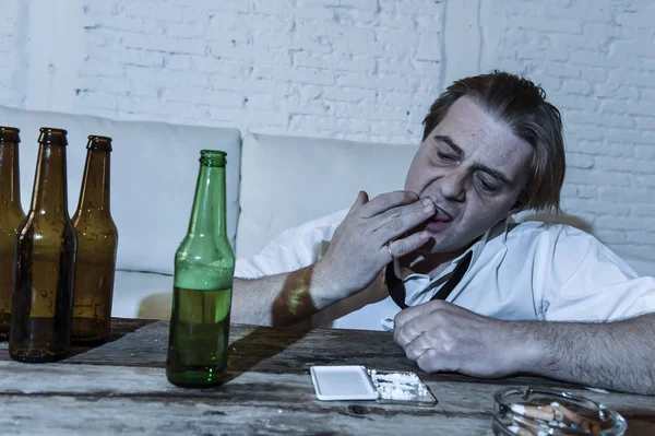 Elpazarolt alkohol és a kábítószer rabja ember laza nyakkendő kokain horkol, és iszik sört palackok otthon — Stock Fotó