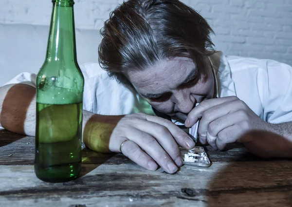 Homem alcoólatra e drogado desperdiçado com gravata solta roncando cocaína e bebendo garrafas de cerveja em casa — Fotografia de Stock