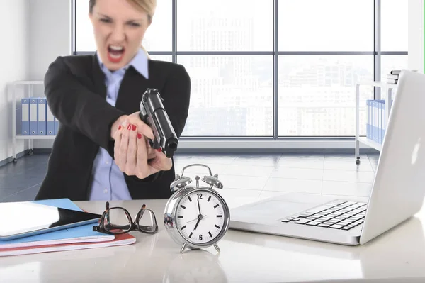 Femme d'affaires furieux et en colère de travailler avec ordinateur portable pointant pistolet à réveil — Photo