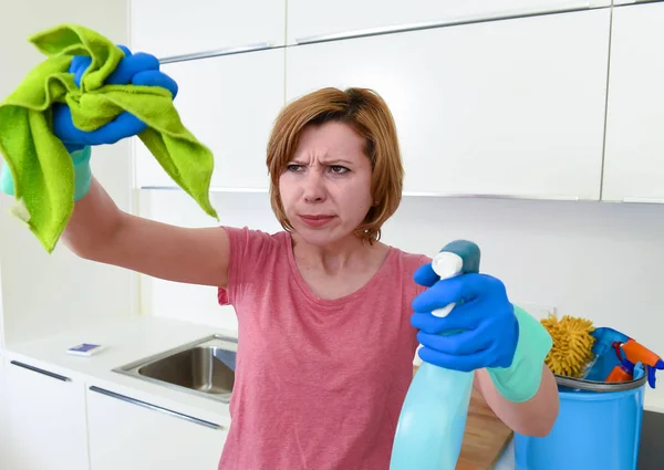 Woman at home kitchen in gloves holding cleaning scourer and detergent spray bottle rubbing with cloth — Stock Photo, Image