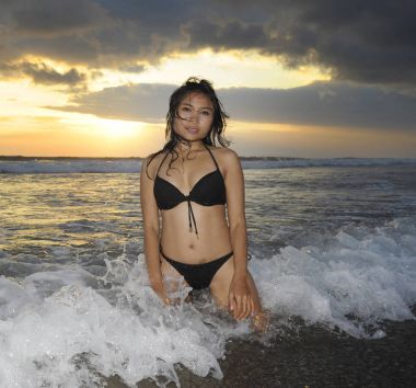 genç güzel ve seksi Asyalı kadın siyah bikini poz içinde günbatımı Plajı Endonezya Bali Adası'nda eğleniyor rahat