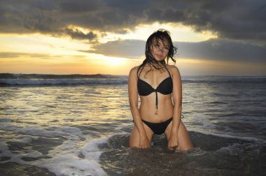 genç güzel ve seksi Asyalı kadın siyah bikini poz içinde günbatımı Plajı Endonezya Bali Adası'nda eğleniyor rahat