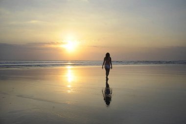 günbatımı plaj güneş ufukta genç güzel Asyalı kadın kum deniz kıyısında özgür ve rahat yürüyüş bakarak