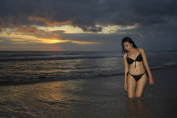 Jeune belle et sexy asiatique femme en bikini noir posant détendu avoir du plaisir à coucher de soleil plage à Bali île de l'Indonésie — Photo