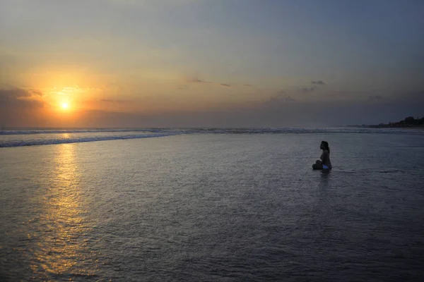 Siluet wanita muda asia cantik duduk di atas air pasir gratis dan santai melihat matahari di pantai matahari terbenam — Stok Foto