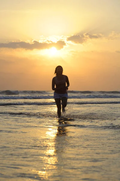 年轻美丽的轮廓和性感的亚洲女人运行自由和快乐，在日落海滩在巴厘岛玩 — 图库照片