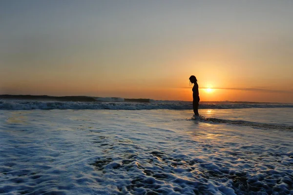 Jeune belle asiatique fille seul à la mer rivage regarder orange ciel coucher de soleil sur l'océan — Photo