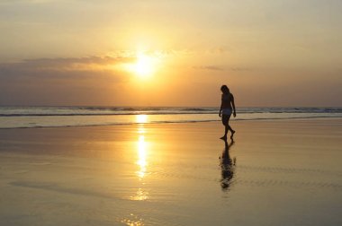 Asyalı genç kadın huzur içinde meditasyon ve özgürlük kavramı Sunset'teki ıssız Sahilde yürüyüş