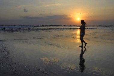 Asyalı genç kadın huzur içinde meditasyon ve özgürlük kavramı Sunset'teki ıssız Sahilde yürüyüş
