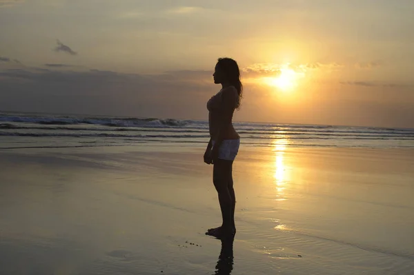 Donna meditando e pensando pacificamente sulla spiaggia deserta al tramonto in meditazione e libertà — Foto Stock