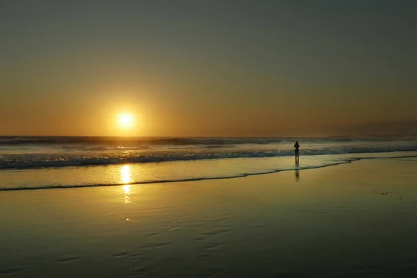 Silhouette einer jungen Frau beim Fotografieren mit dem Handy von einem wunderschönen Sonnenuntergang am Strand — Stockfoto