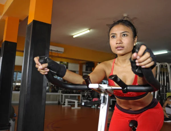 Young beautiful and sweaty Asian active woman training hard cycling and riding on static bike workout at gym — Stock Photo, Image